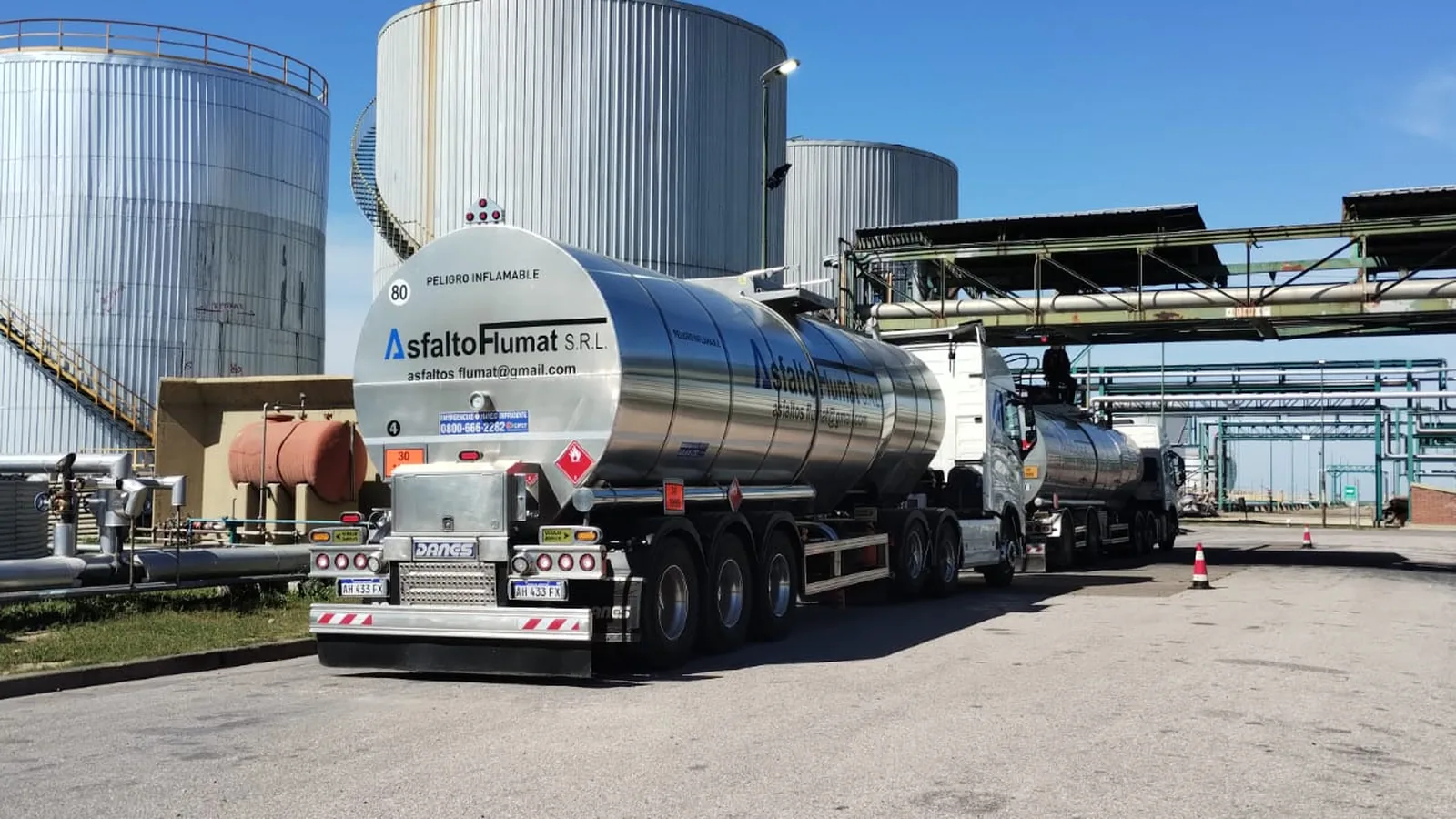 Equipo cisterna de Asfalto Flumat maniobrando entre los tanques verticales de almacenaje de una planta de combustibles.