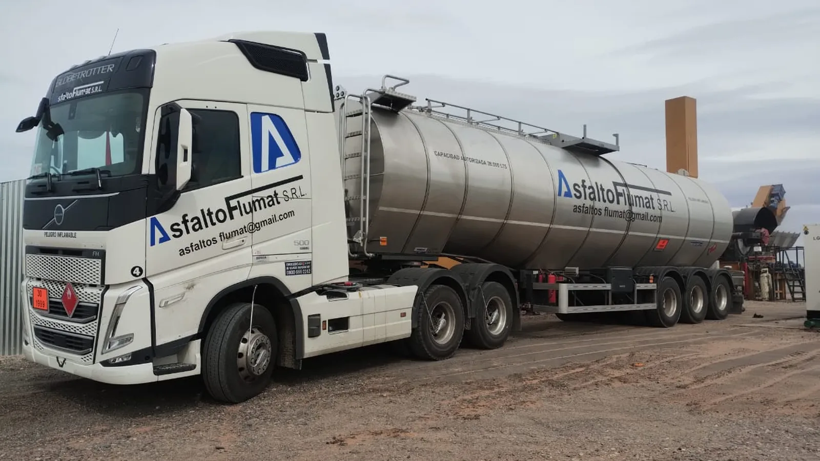 Frente de un tractor Volvo FH de Asfalto Flumat con la razón social y el correo de contacto rotulados sobre la puerta, enganchado a la cisterna.