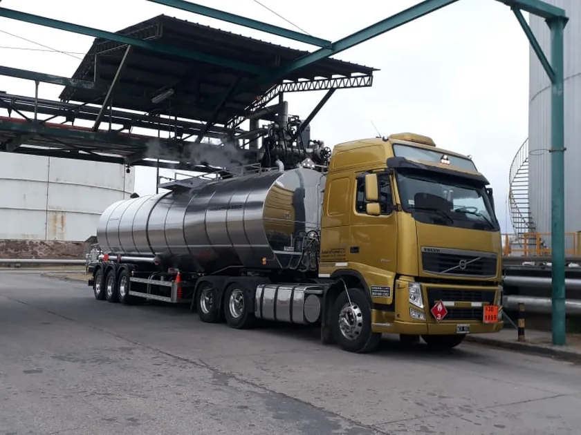 Unidad completa de Asfalto Flumat: tractor Volvo con semirremolque cisterna de acero inoxidable en la playa de una planta.