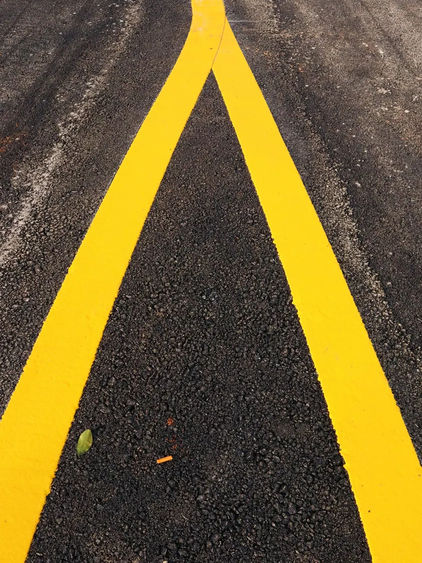 Demarcación vial amarilla recién aplicada sobre una calzada asfáltica.